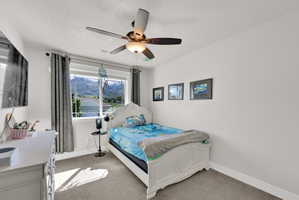 Window offering mountain scenery, light gray carpeting, ceiling fan with integrated lighting, white baseboards, and white painted walls