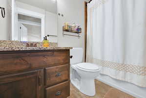 Bathroom featuring a wood-finish vanity with drawer storage, speckled stone countertop, and an integrated basin