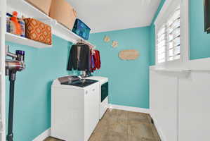 Dedicated laundry space featuring a white top-load washer, a white front-load dryer, and overhead shelving