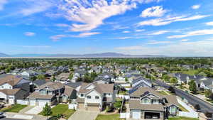 Residential street featuring multiple single-family homes with pitched roofs, integrated garages, and landscaped front yards
