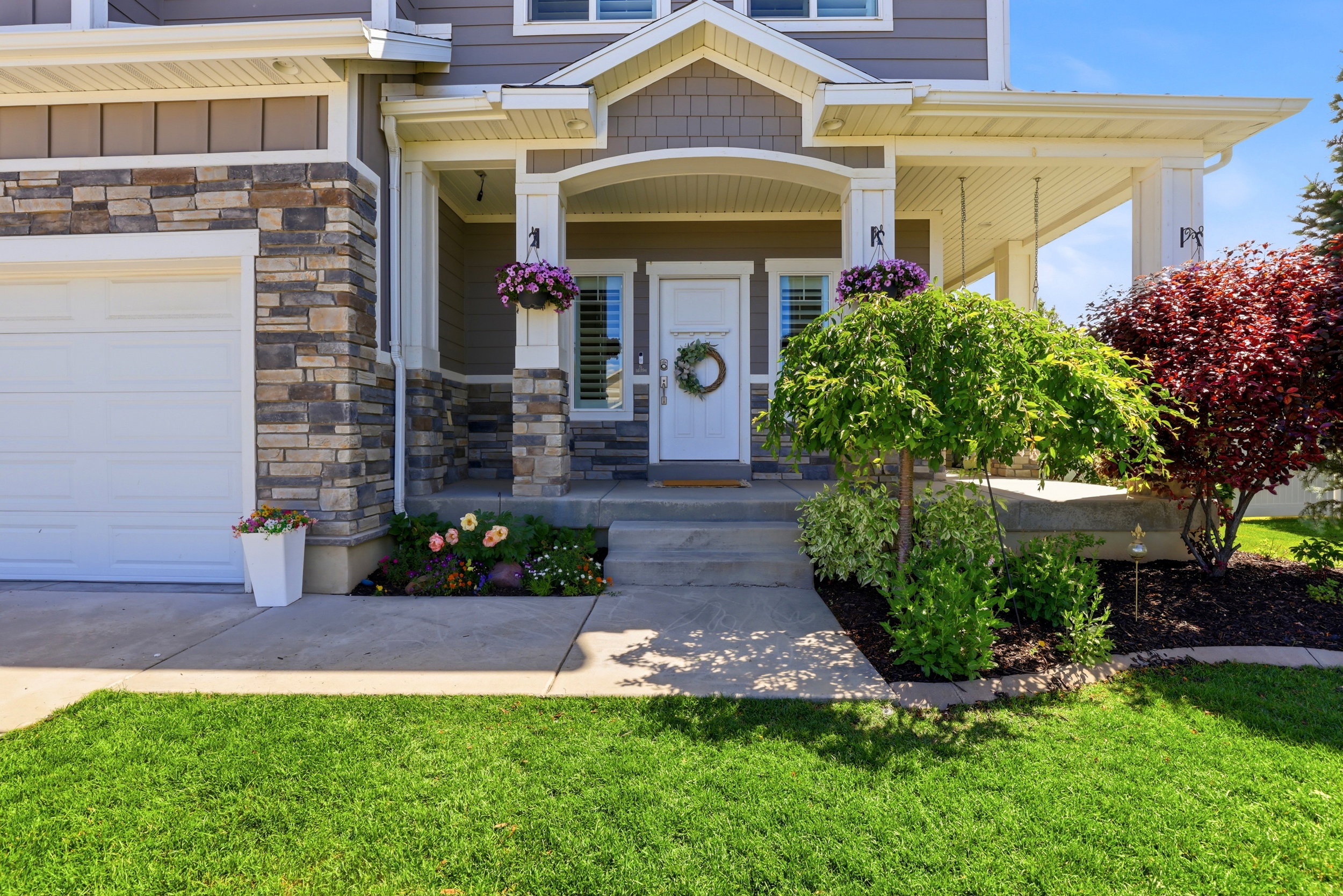 Inviting front porch featuring a white entry door with sidelights, decorative columns, and a stone facade