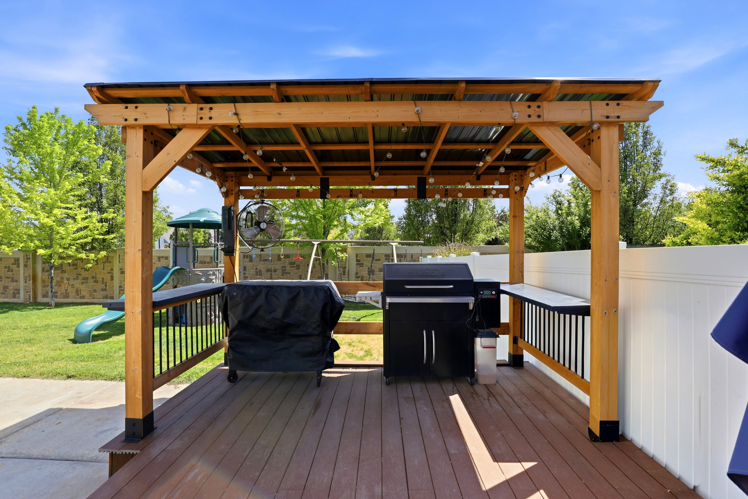 Expansive outdoor living area featuring a wood-toned deck and a built-in pergola with a metal roof