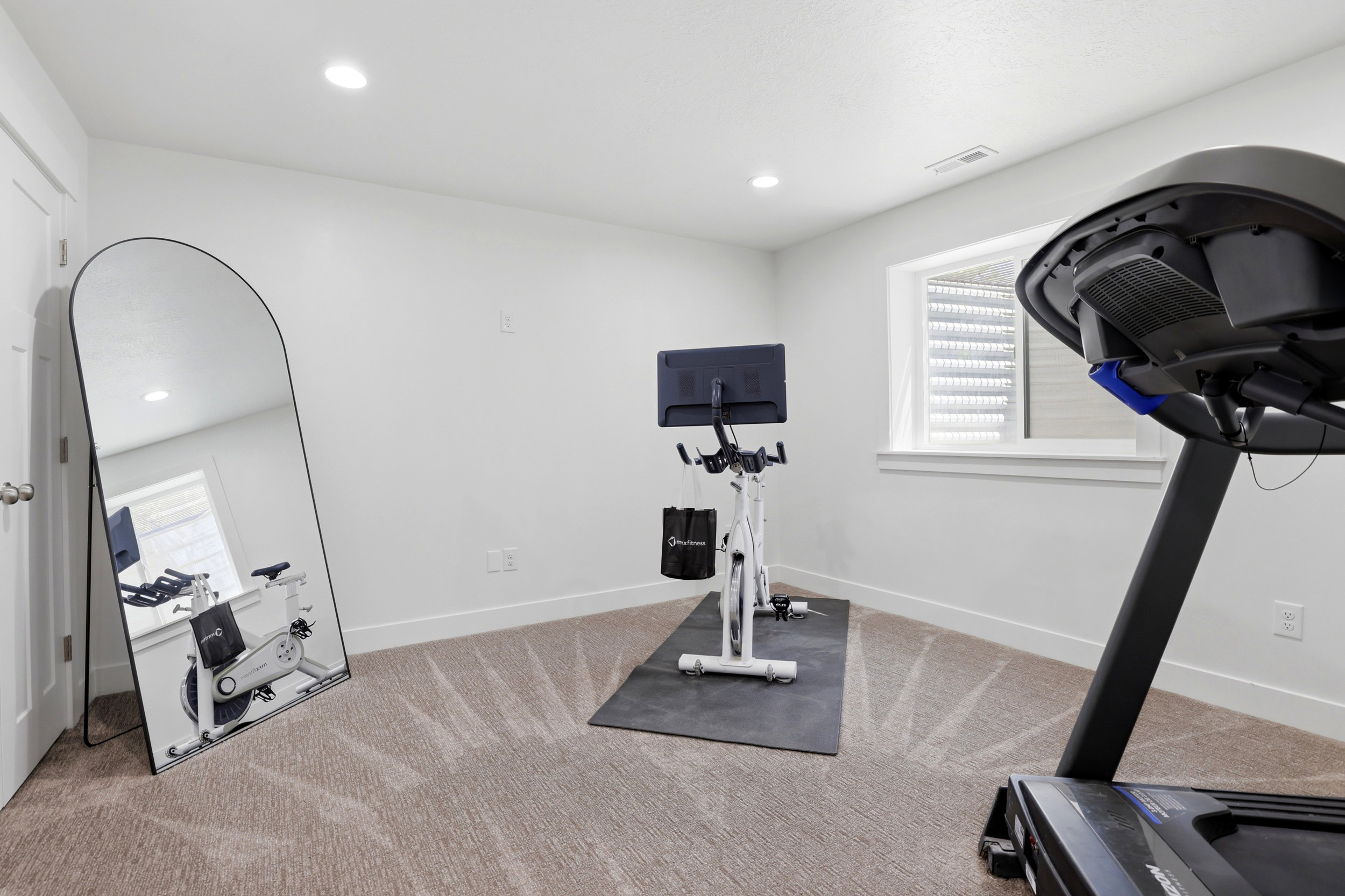 Carpeted room with white walls, recessed lighting, and a single window with a privacy blind
