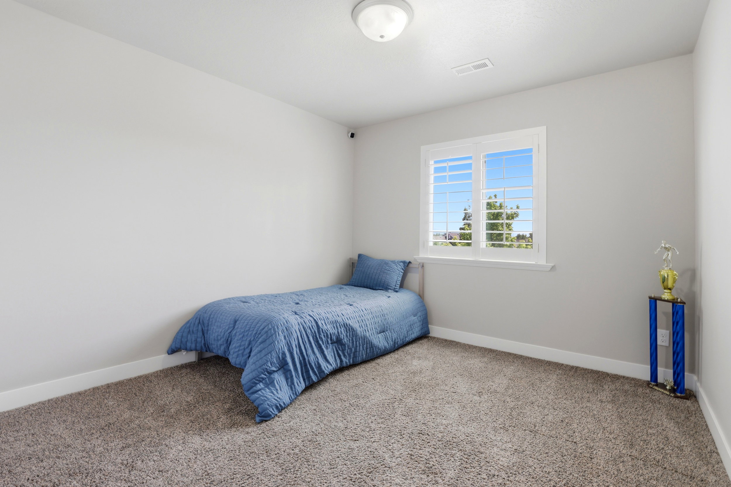 Bedroom featuring a window with white shutters, light gray walls, and carpet flooring