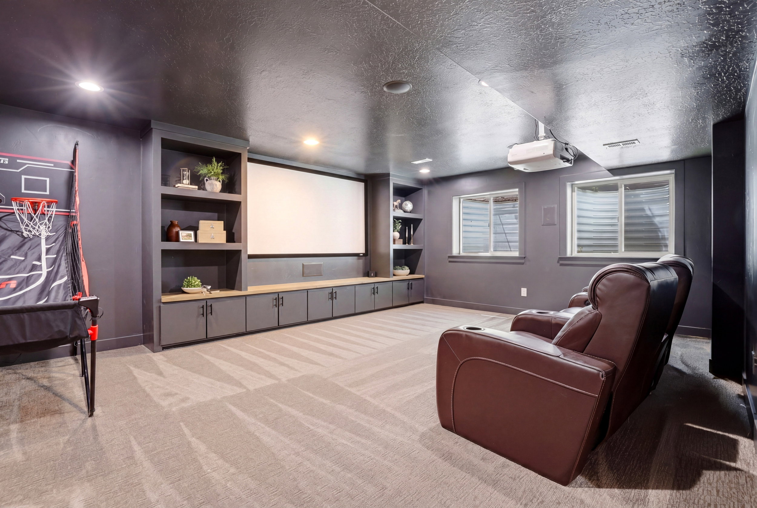 Entertainment room featuring a large projection screen, built-in cabinetry with open shelving, recessed lighting, and carpet flooring