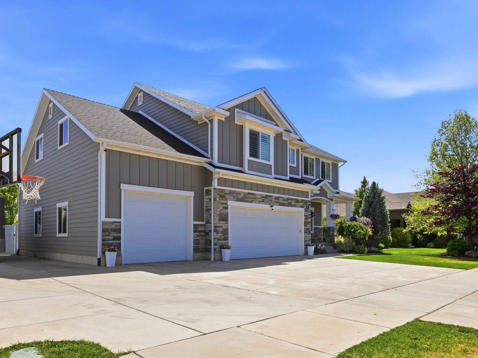 Contemporary home featuring a dual garage, a spacious concrete driveway, and a well-maintained lawn
