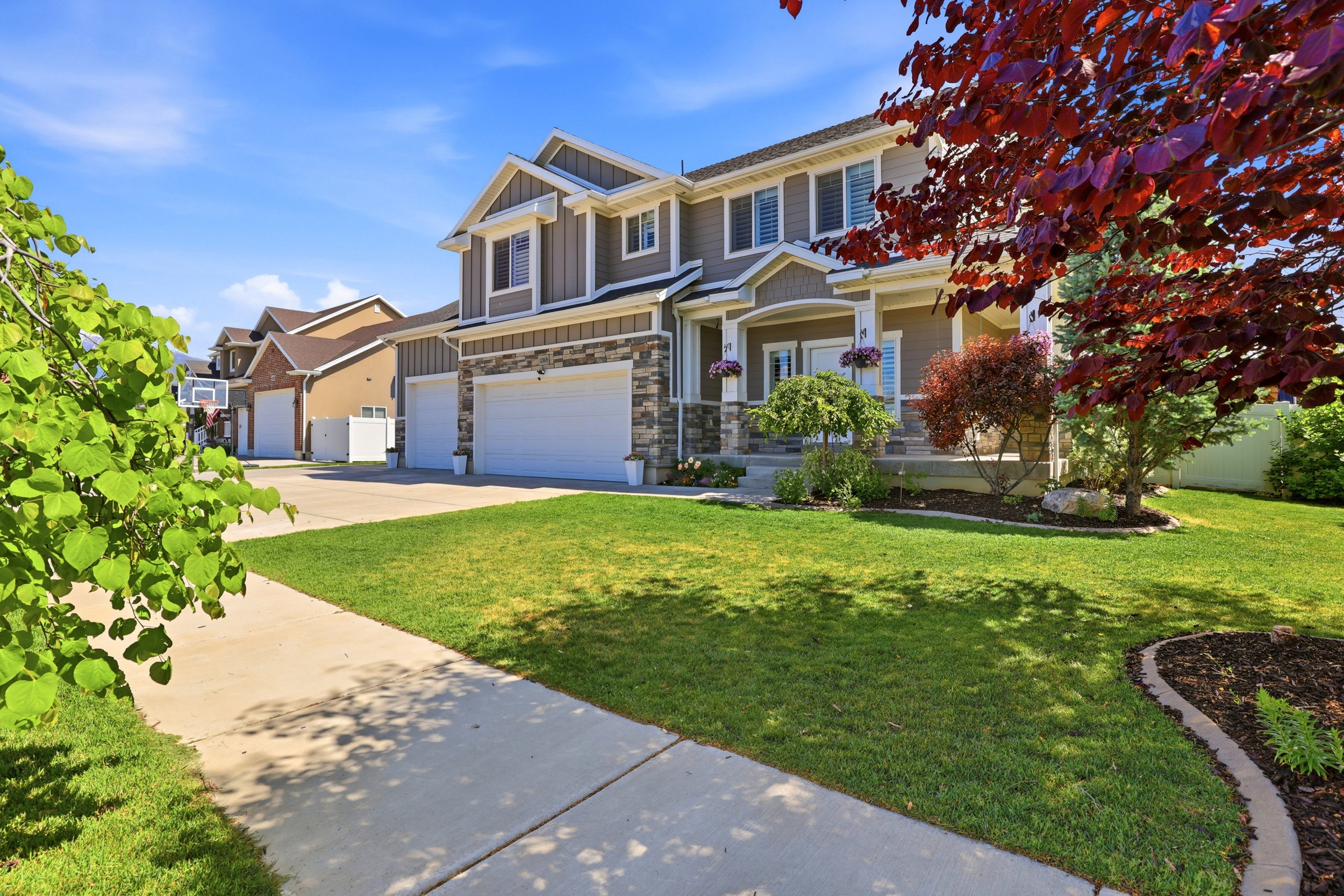 Two-story residence featuring a stone and siding facade, covered front porch, and an attached three-car garage
