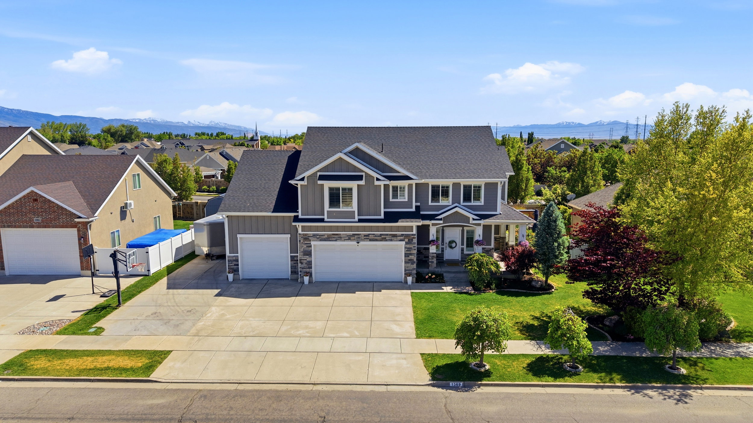 Contemporary two-story residence featuring a gray exterior with stone accents and a dark shingle roof