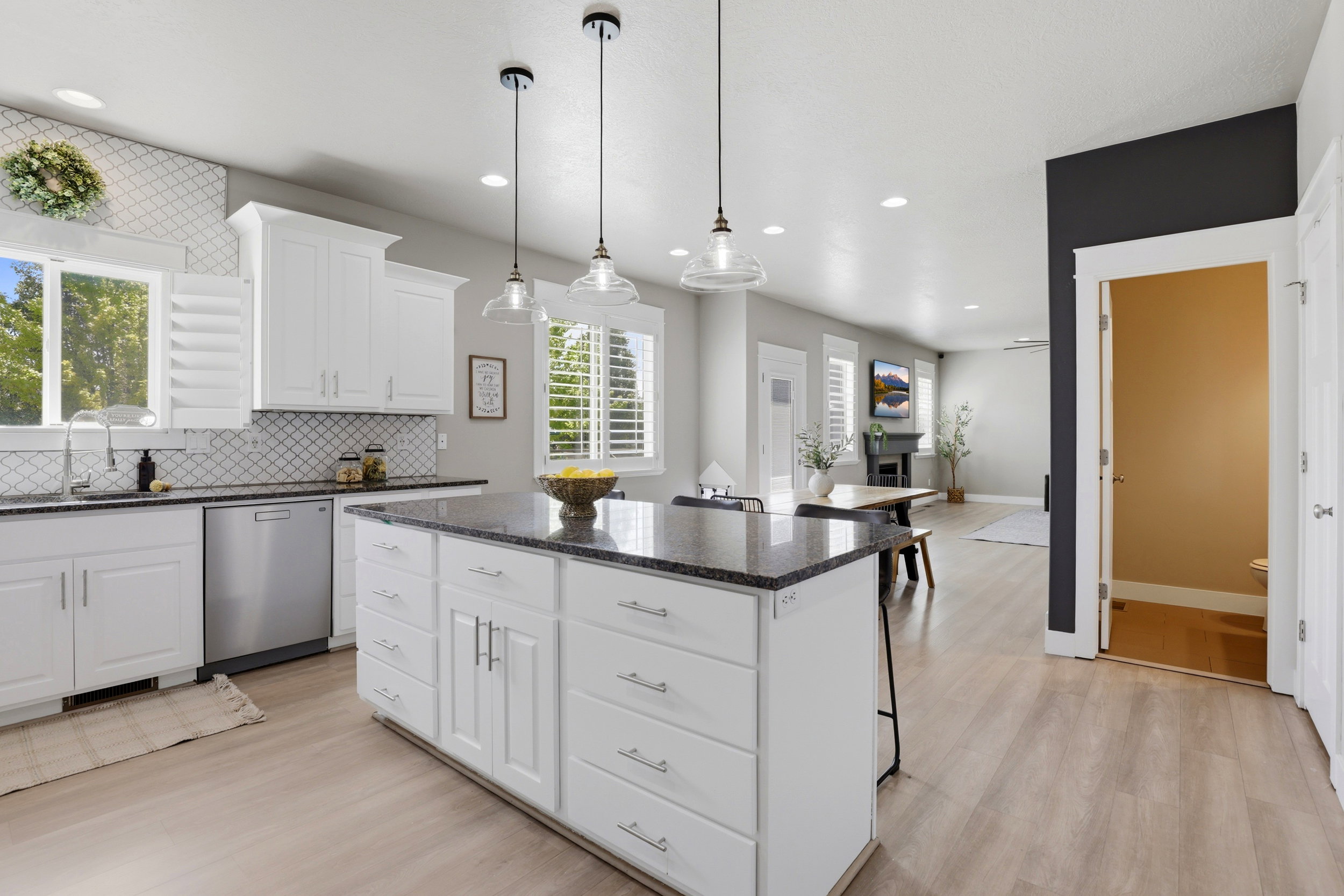 Kitchen featuring white cabinetry, dark stone countertops, stainless steel appliances, and wood-finish flooring
