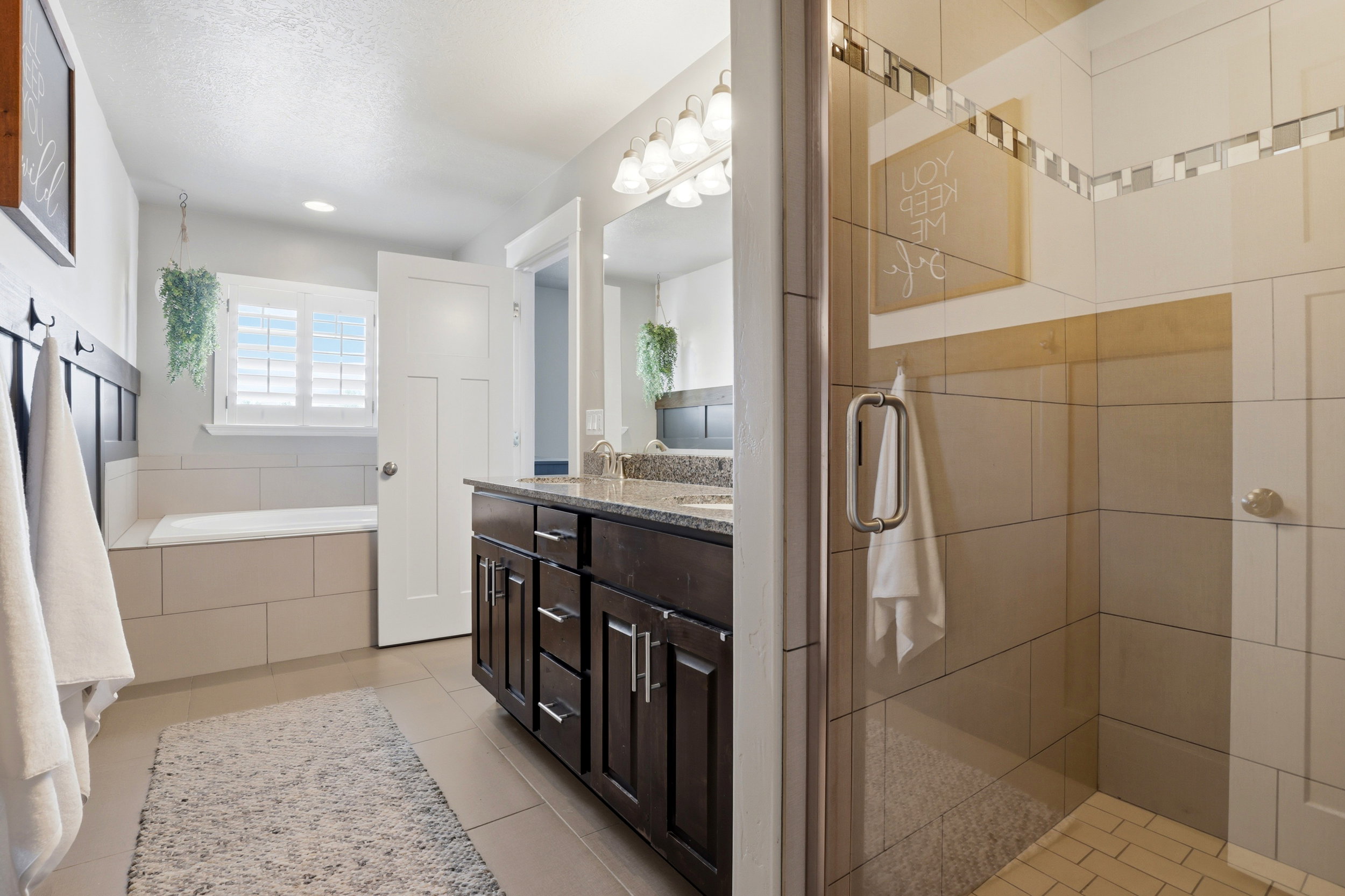 Bathroom featuring a freestanding tub with a tiled surround, a dark wood vanity with a stone countertop, and a glass-enclosed shower