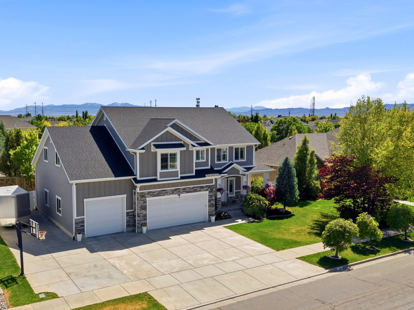 Two-story residence featuring grey siding, dark shingle roofing, and stone accents
