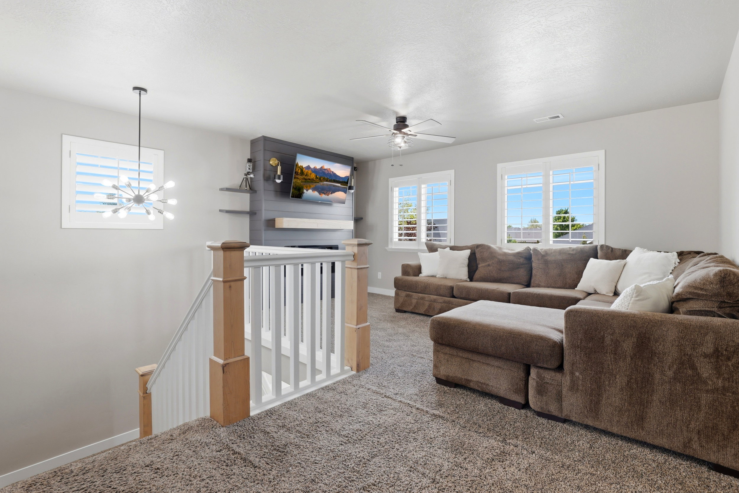 Upper-level living space featuring a contemporary light fixture, a ceiling fan, and multiple windows with white plantation shutters