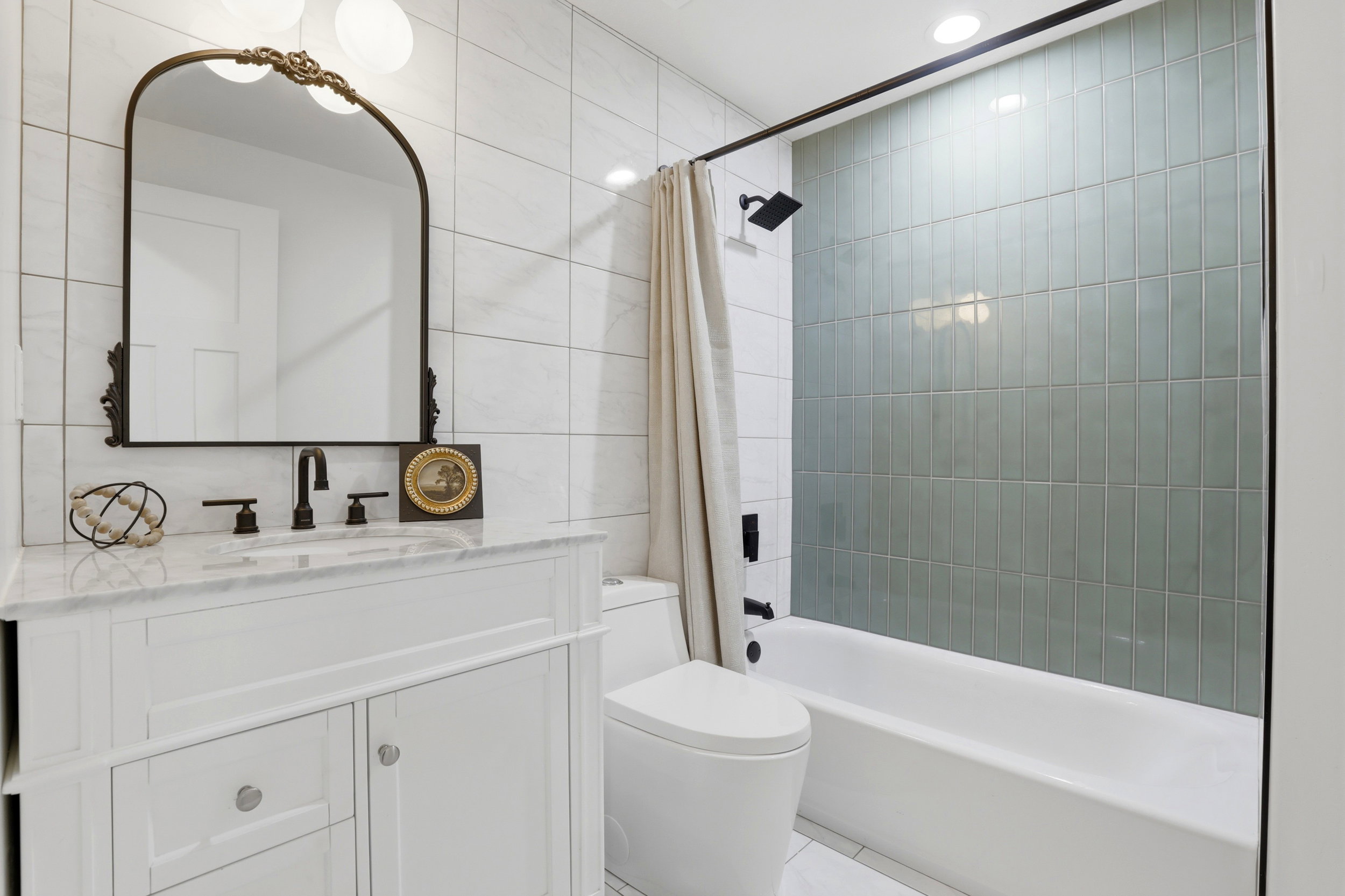 Bathroom featuring a white vanity with a stone countertop, a decorative framed mirror, and matte black fixtures