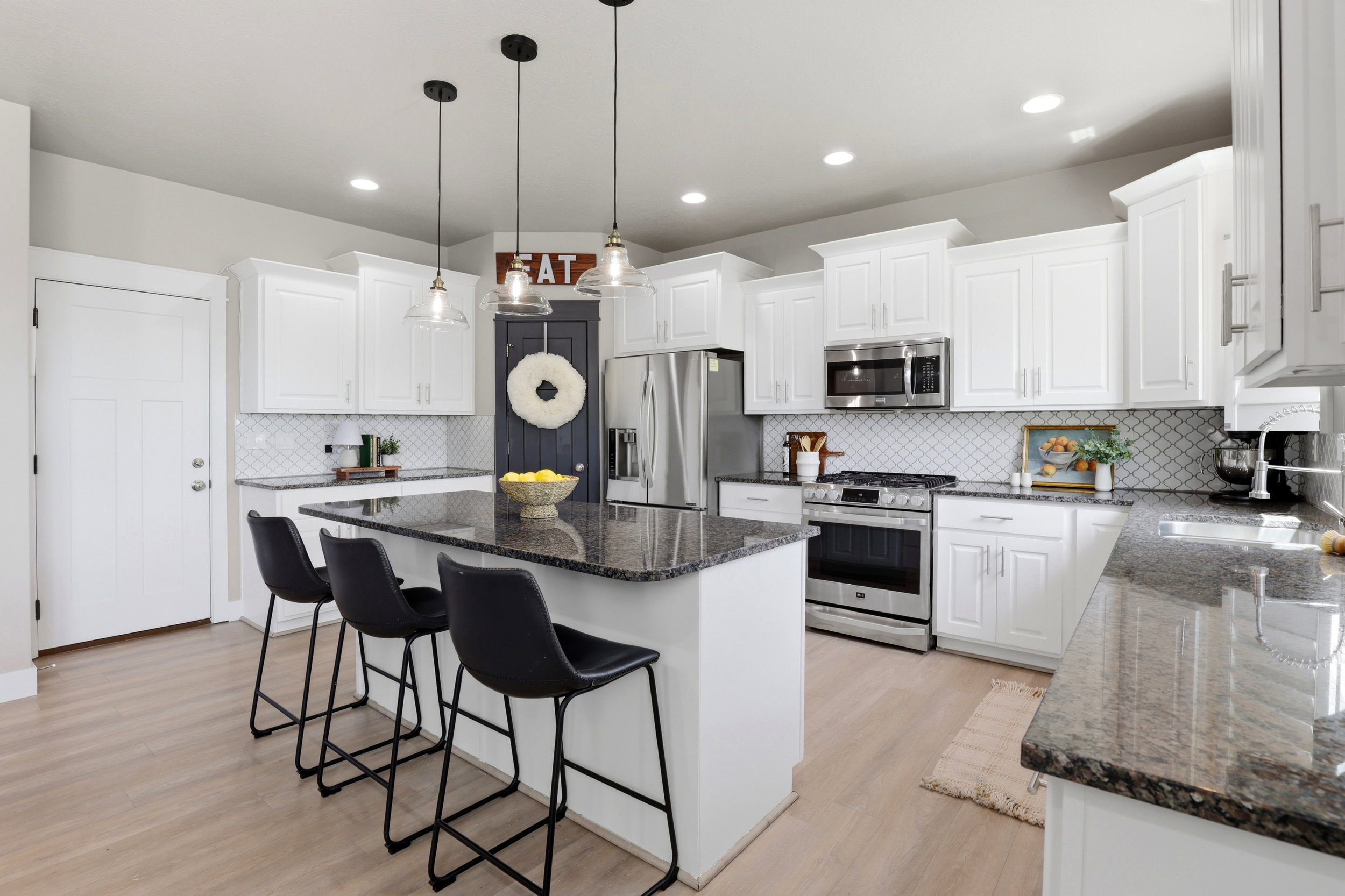 Contemporary kitchen featuring light wood-finish flooring, white shaker-style cabinetry, and dark speckled countertops