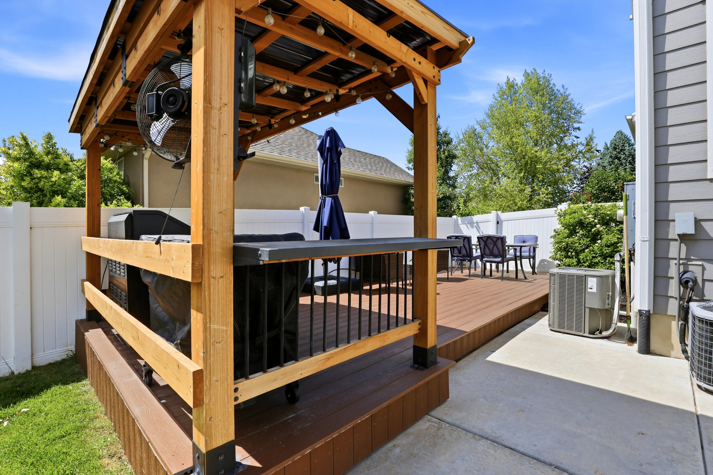 Expansive outdoor deck featuring a covered pergola, string lighting, and wood-finish flooring