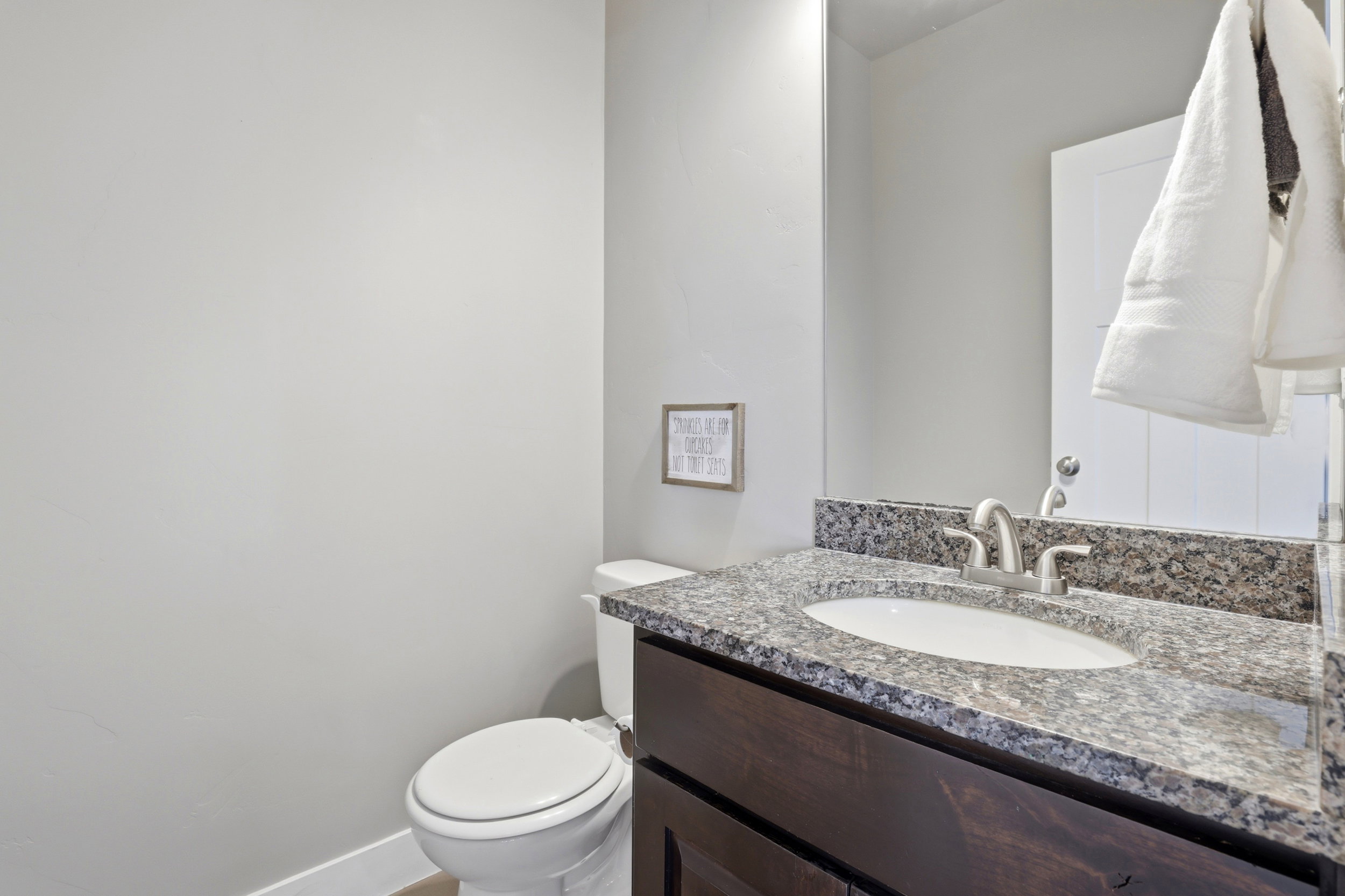 Bathroom featuring a dark wood-finish vanity with a granite countertop, undermount sink, and brushed nickel faucet