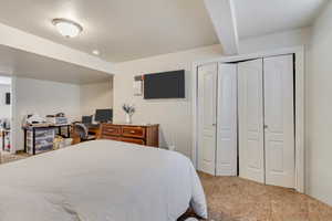 Carpeted bedroom featuring bi-fold closet doors, a flush-mount ceiling light fixture, and a neutral color palette