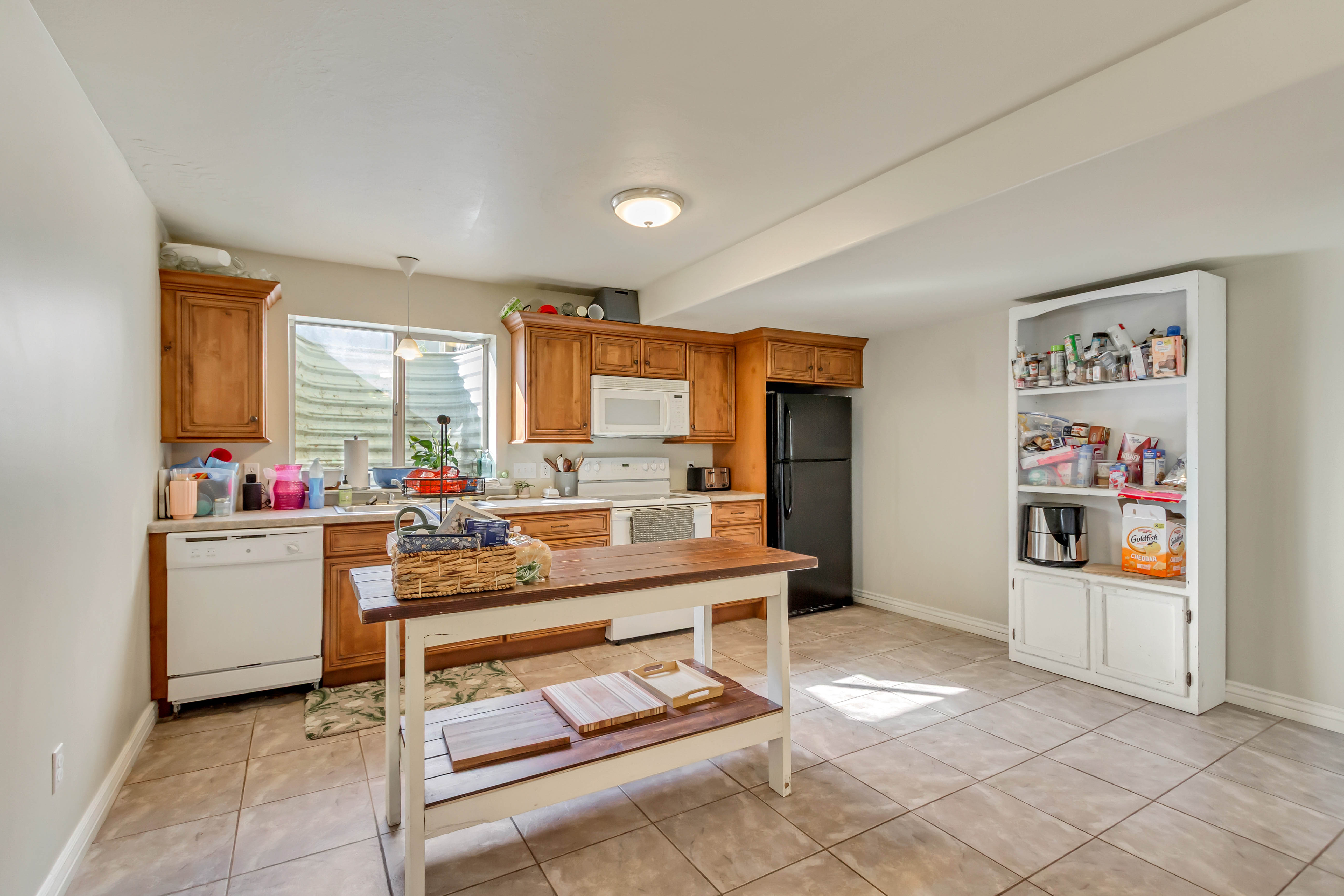 Kitchen featuring wood cabinetry, white appliances, and light-toned tile flooring