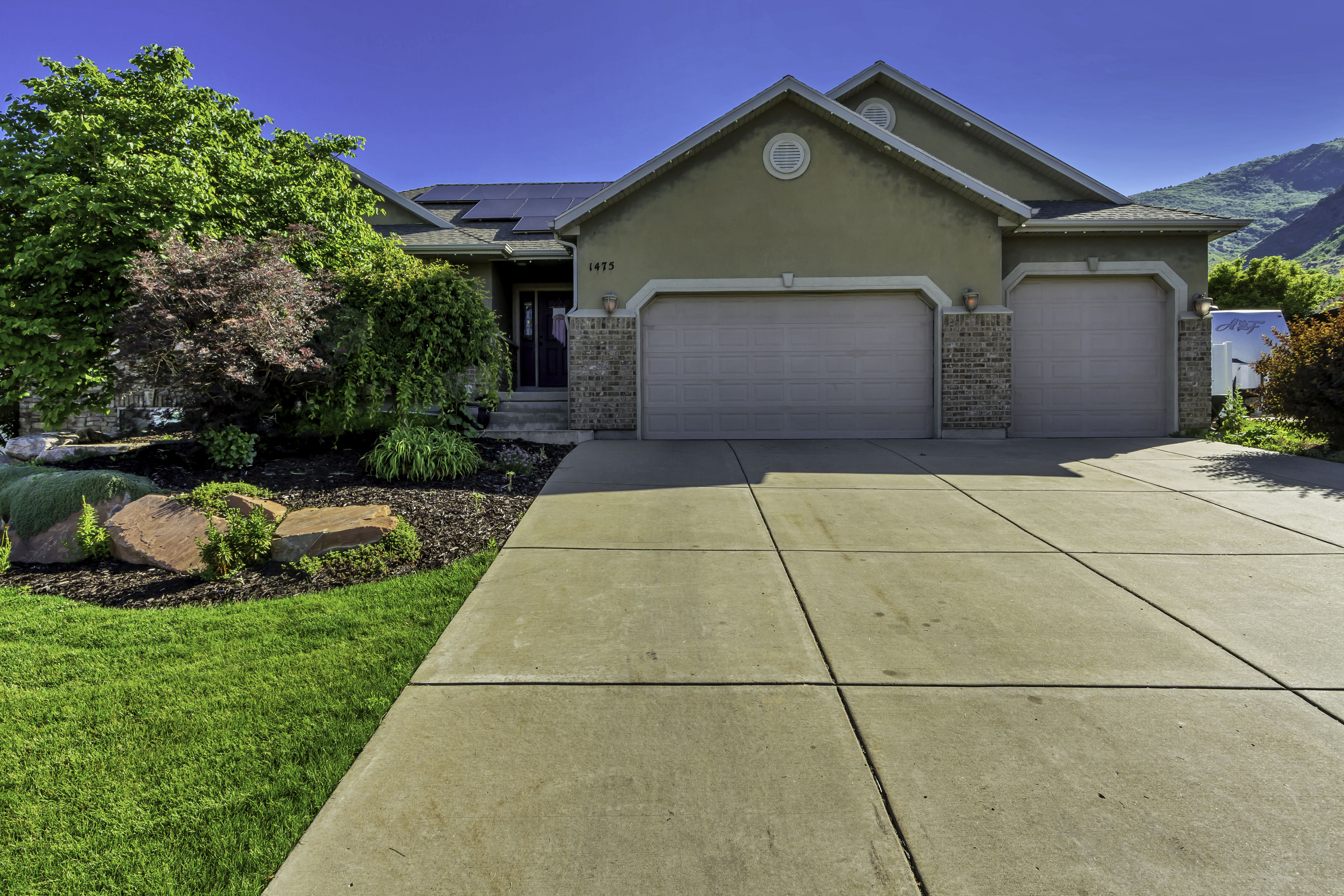 Stucco and brick facade residence featuring a two-car garage, concrete driveway, and front landscaping