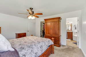 Carpeted bedroom featuring a ceiling fan with light fixture, white walls, and a walk-in closet