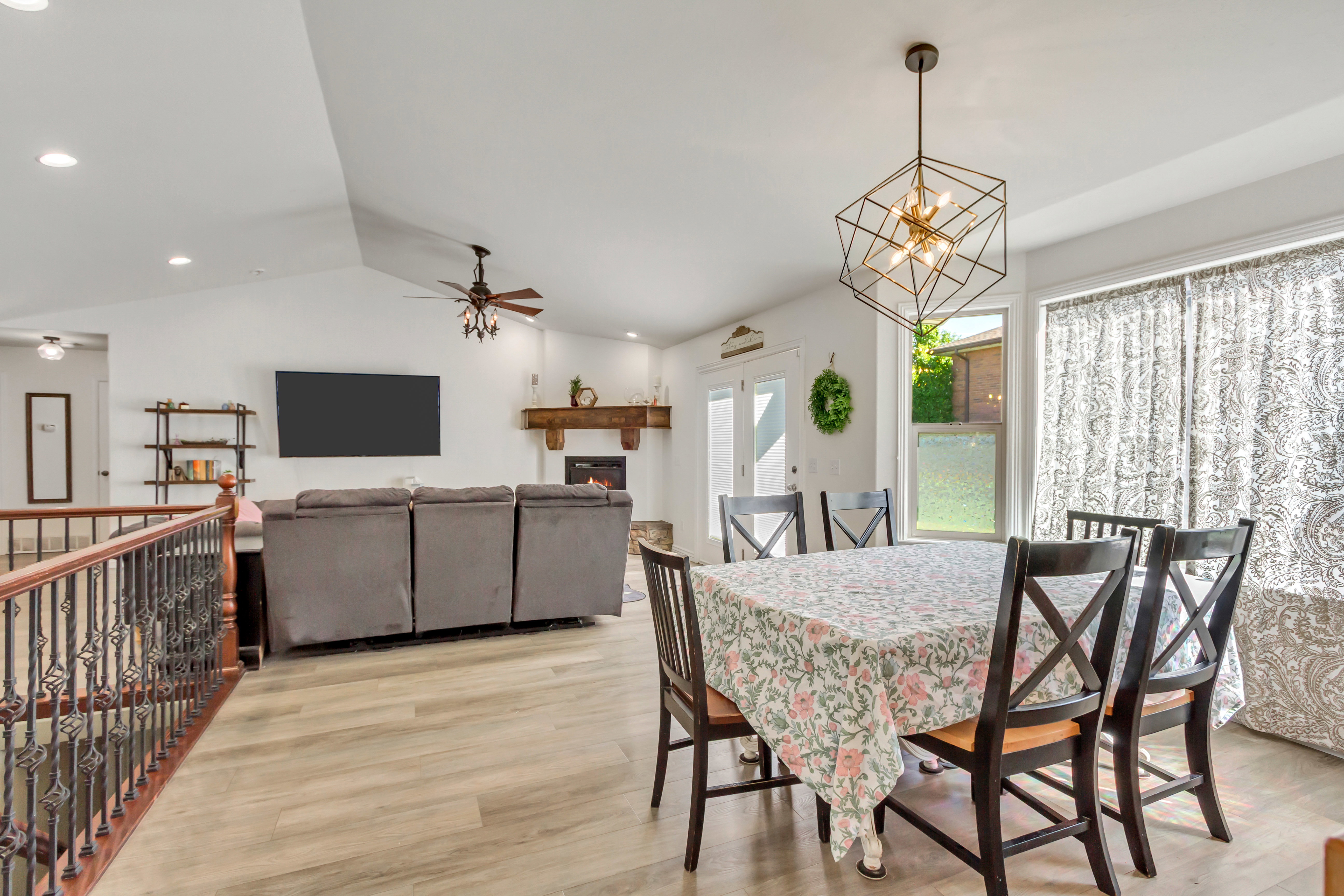 Open-concept living area featuring vaulted ceilings, wood-finish flooring, and a decorative fireplace with a substantial wood mantel