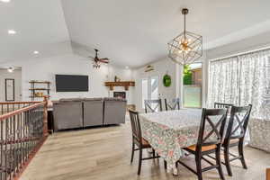 Open-concept living area featuring vaulted ceilings, wood-finish flooring, and a decorative fireplace with a substantial wood mantel