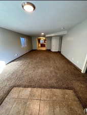 Expansive room featuring plush brown carpeting and a tiled entry