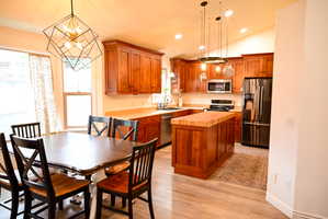 Open-concept kitchen and dining area featuring wood-finish flooring, recessed lighting, and a vaulted ceiling