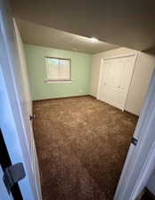 Spacious room featuring brown carpeting, a window with white trim, and a bi-fold closet with white paneled doors