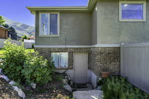 Stucco and brick exterior with multiple windows and a private entry door