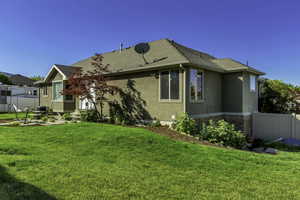 Exterior featuring stucco siding, a composition shingle roof, bay windows, and a landscaped yard with mature plantings