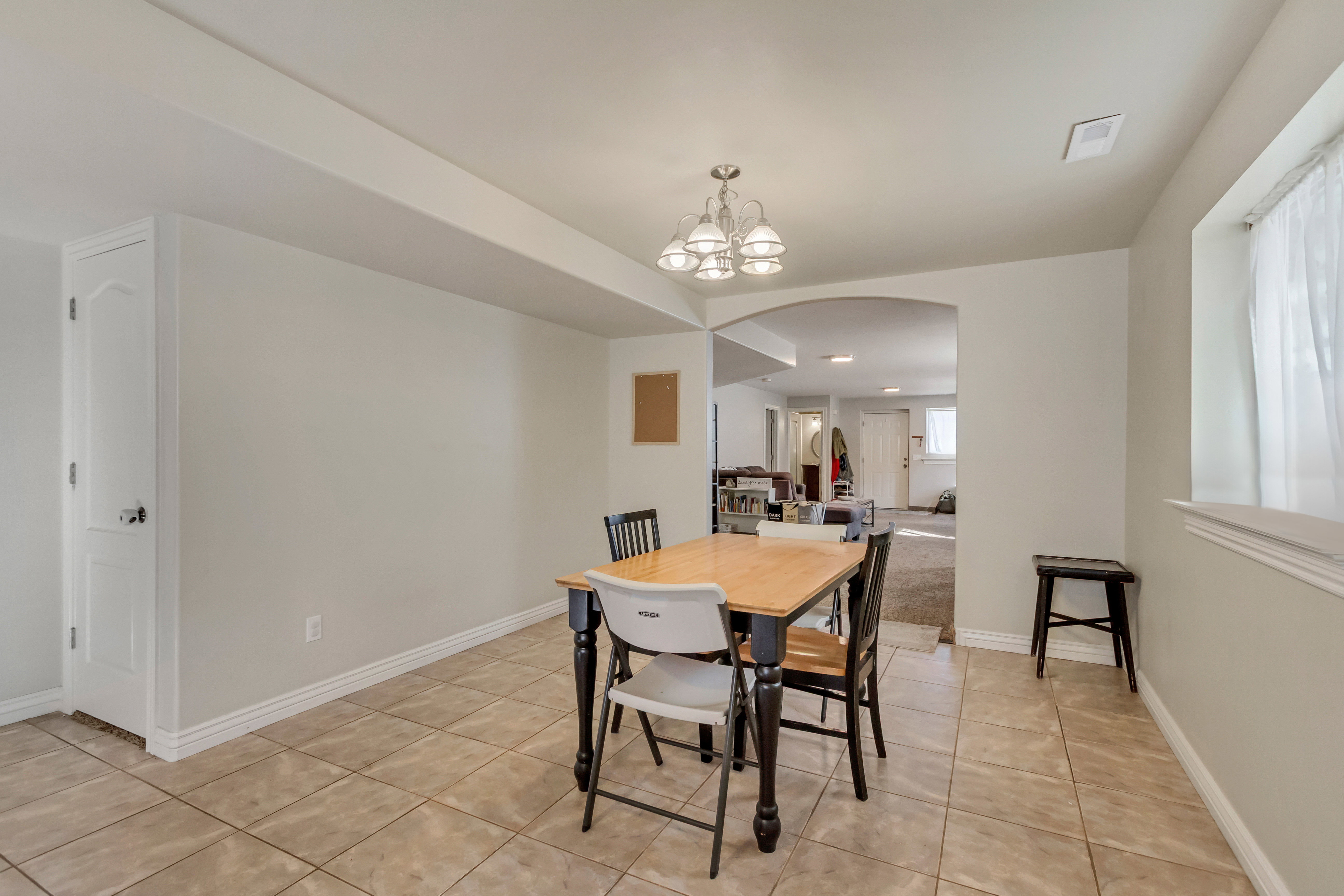 Tiled flooring extending into an archway, featuring a built-in storage cabinet with a white paneled door
