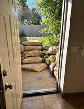 Outdoor access featuring natural stone steps and a private fenced yard with mature trees