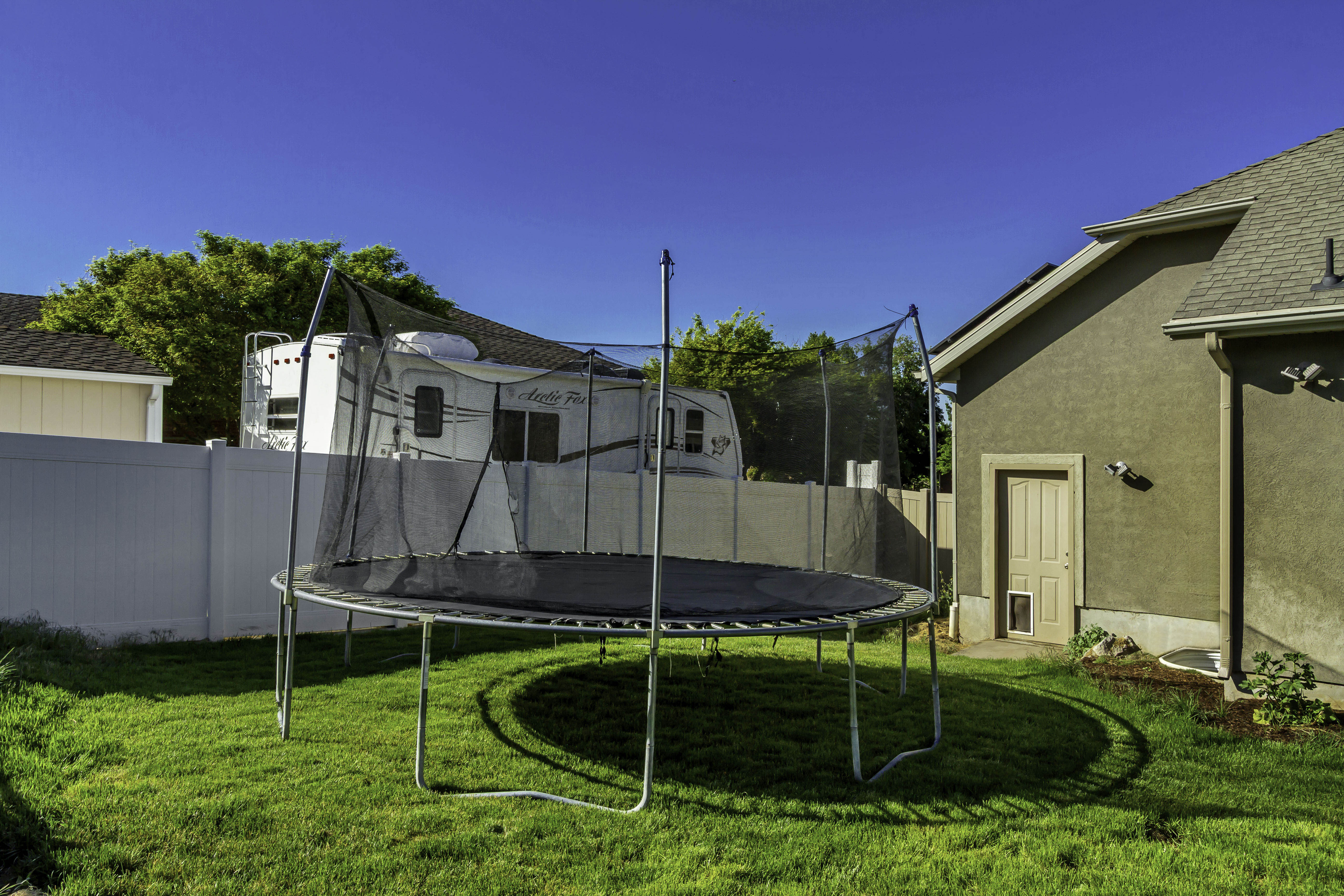 Expansive backyard featuring a lush green lawn, a stucco exterior, and a privacy fence