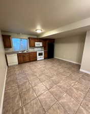 Kitchen area featuring tile flooring, wood cabinetry, a white dishwasher, a white range, and a black refrigerator