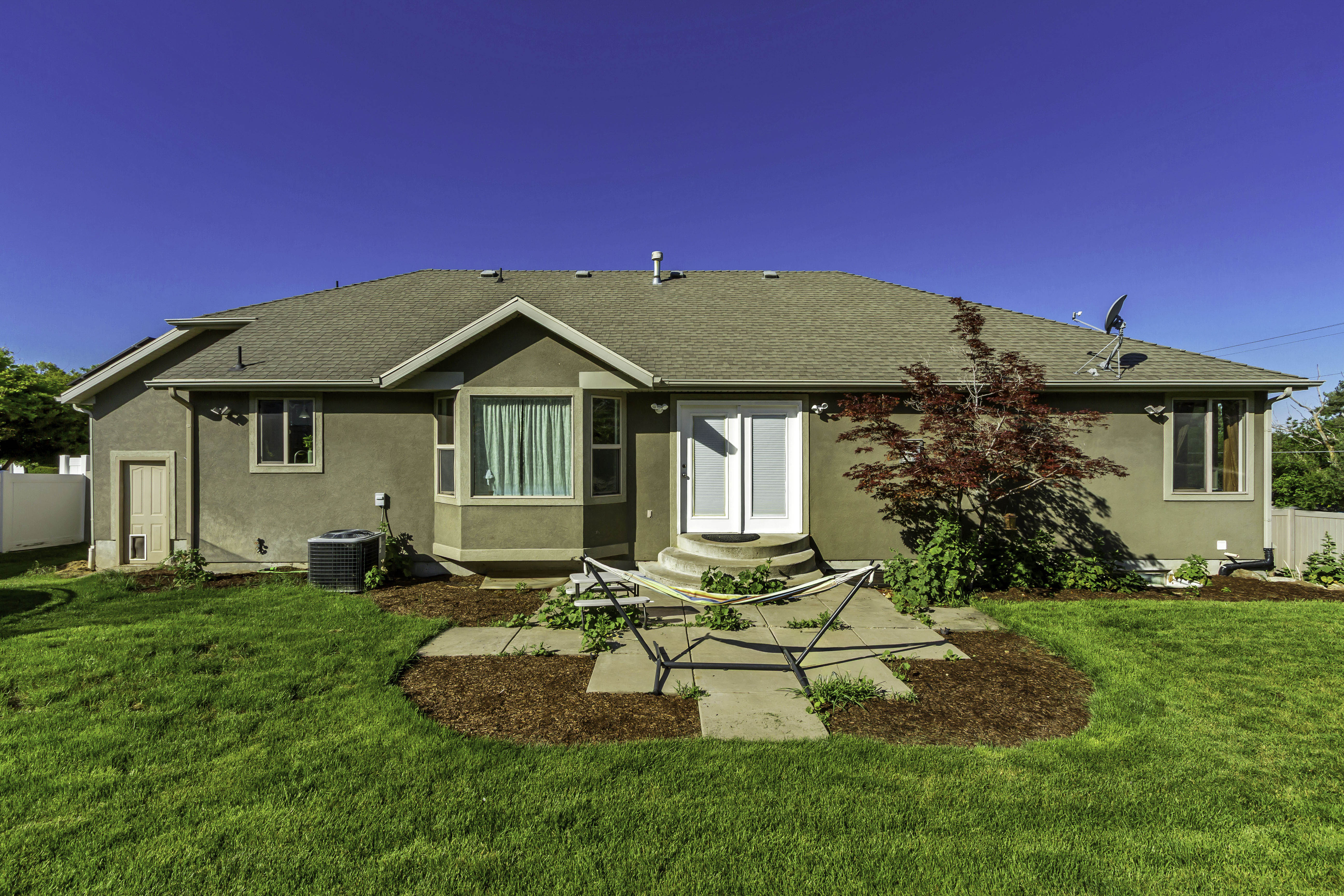 Rear exterior featuring stucco siding, a bay window, and a white double door