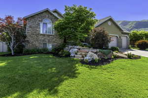 Stone facade residence featuring an arched window and an attached multi-car garage with stone accents