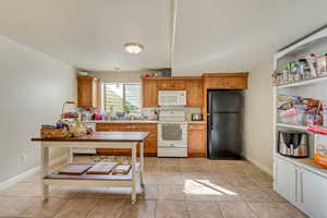 Kitchen featuring wood cabinetry, white appliances, and a black refrigerator