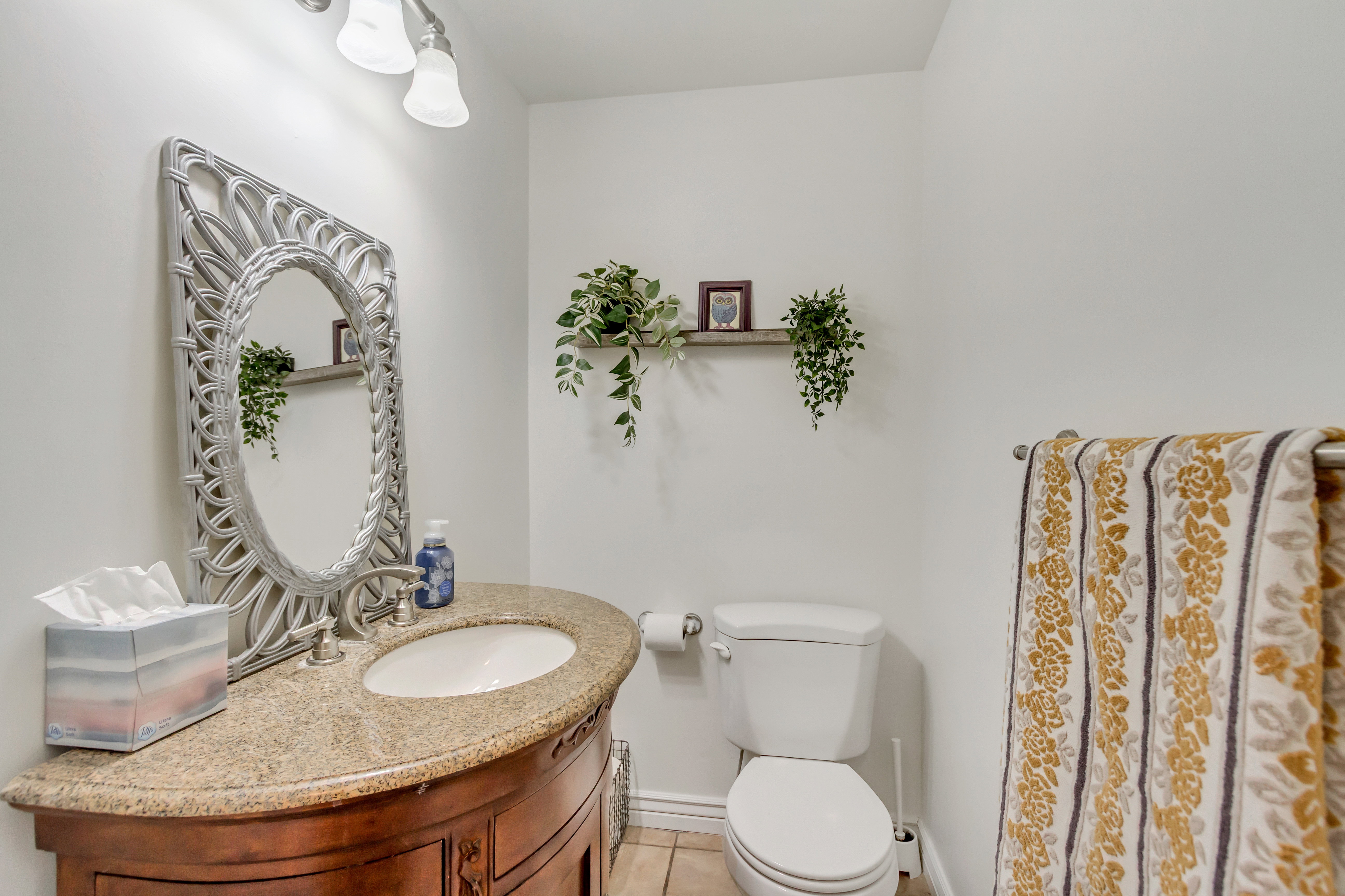 Bathroom featuring a curved wood-finish vanity with an undermount sink, a light-toned countertop, and an ornate silver-framed mirror