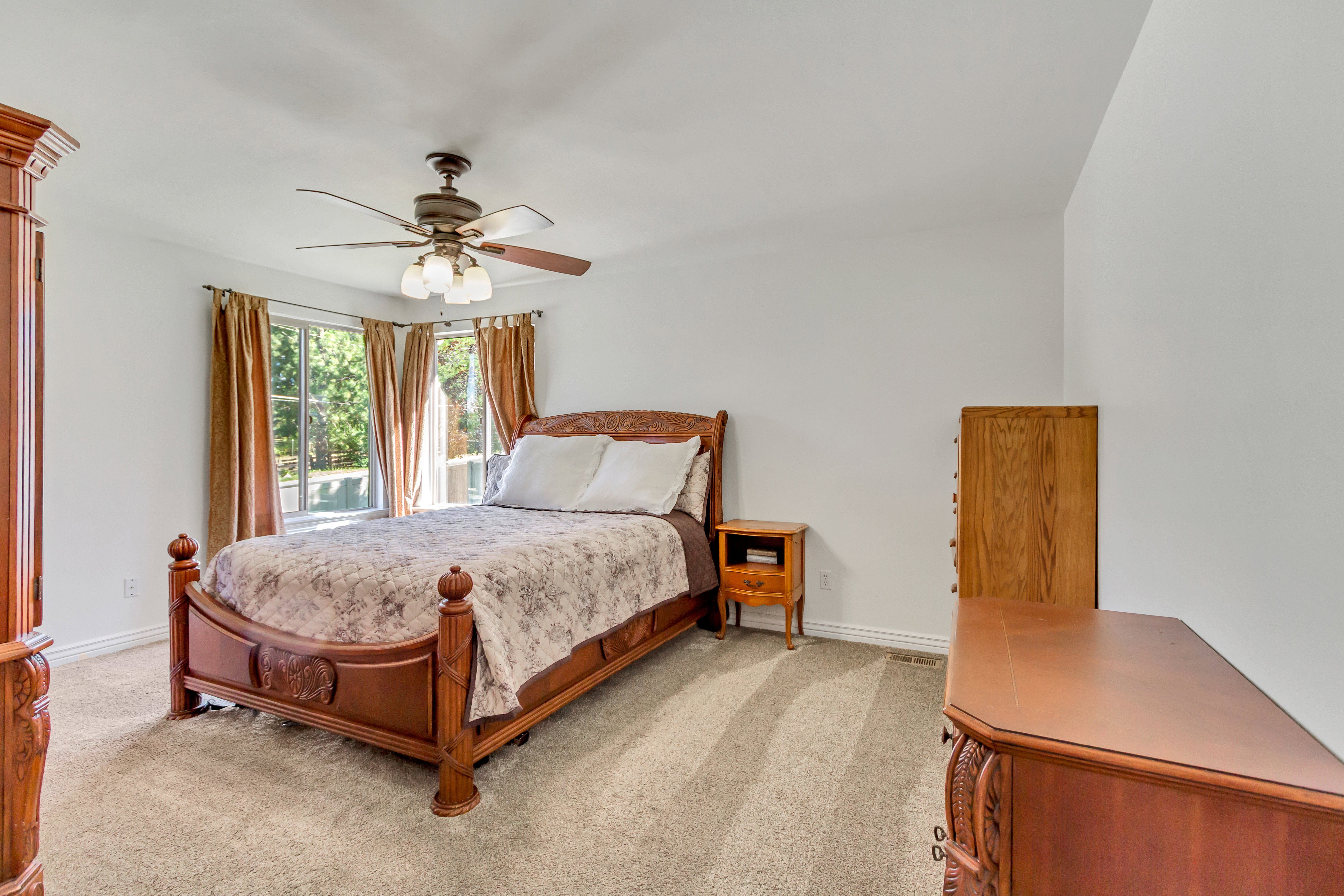 Spacious room featuring a bay window, ceiling fan, and neutral carpet flooring
