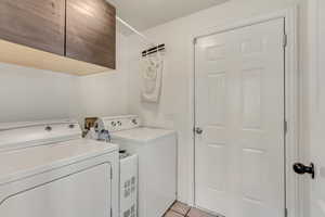 Laundry area featuring wood-finish upper cabinetry, a white panel door, and tile flooring