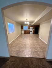 Open-concept kitchen and living area featuring brown wood cabinetry, white appliances, and a tile floor