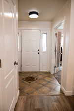 Entryway featuring a paneled door with sidelights, a modern flush-mount light fixture, and tile flooring with a decorative inlay