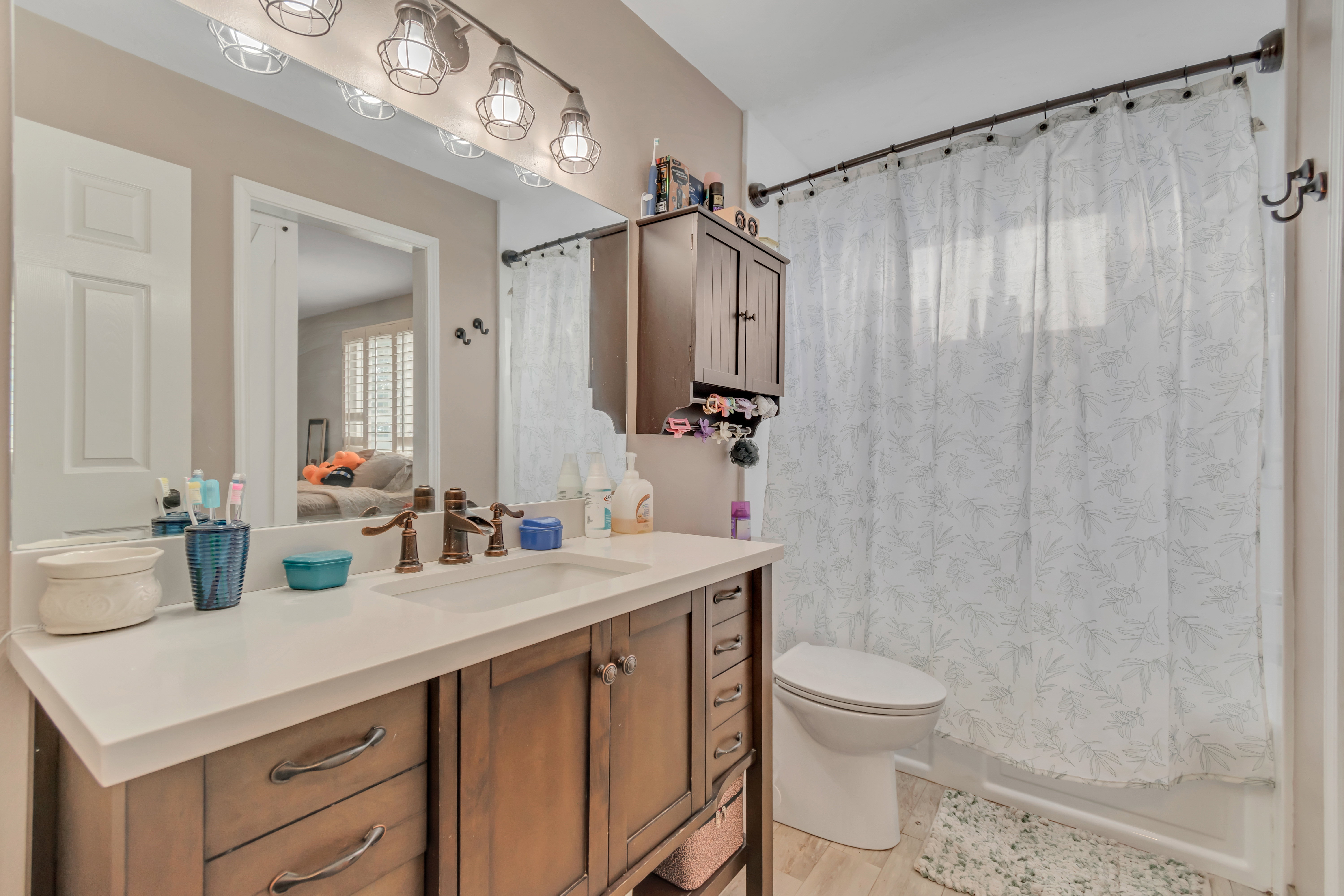 Bathroom vanity with a white countertop and a bronze-finish faucet