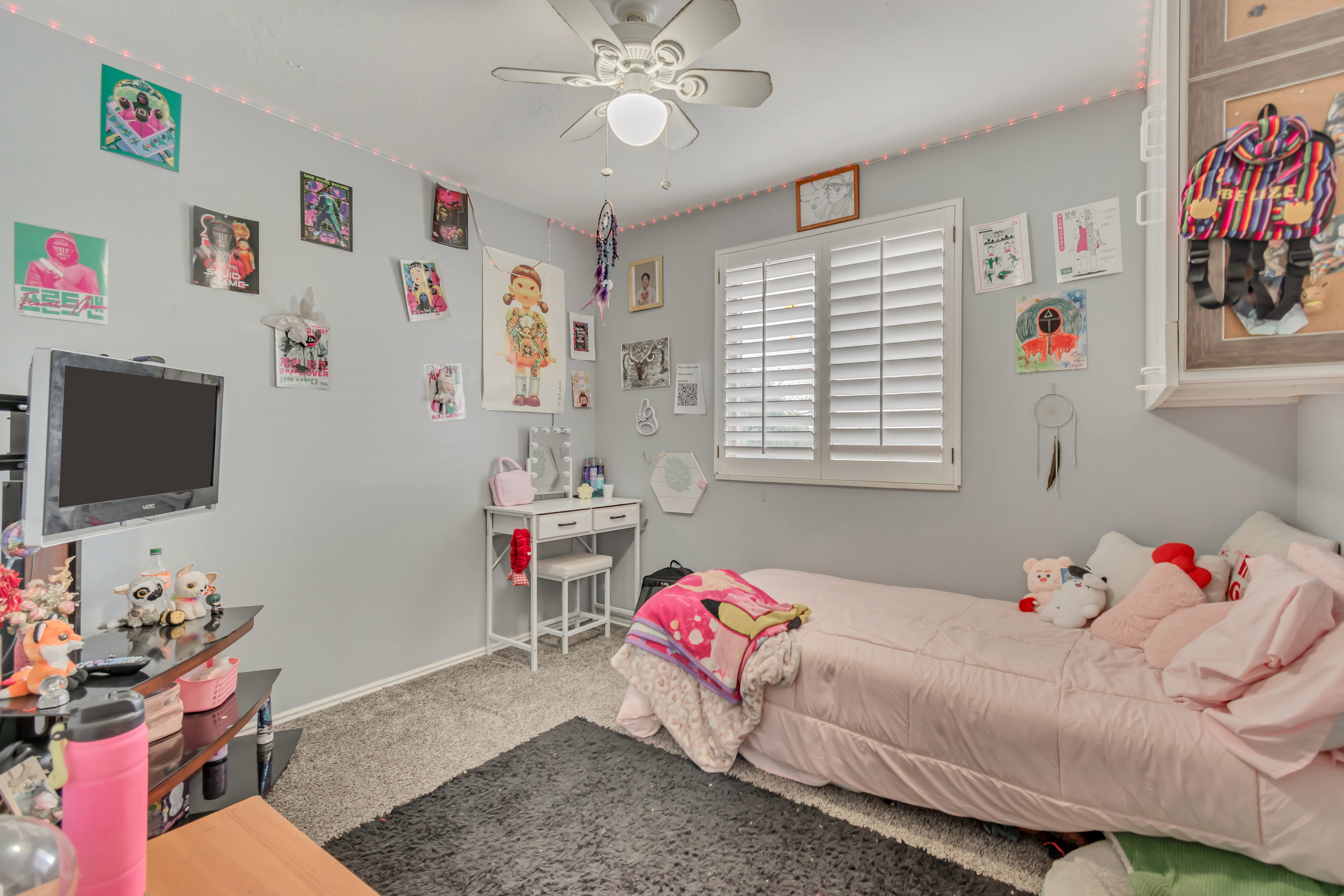 Carpeted room featuring a ceiling fan with integrated lighting, a window with white plantation shutters, and light gray painted walls
