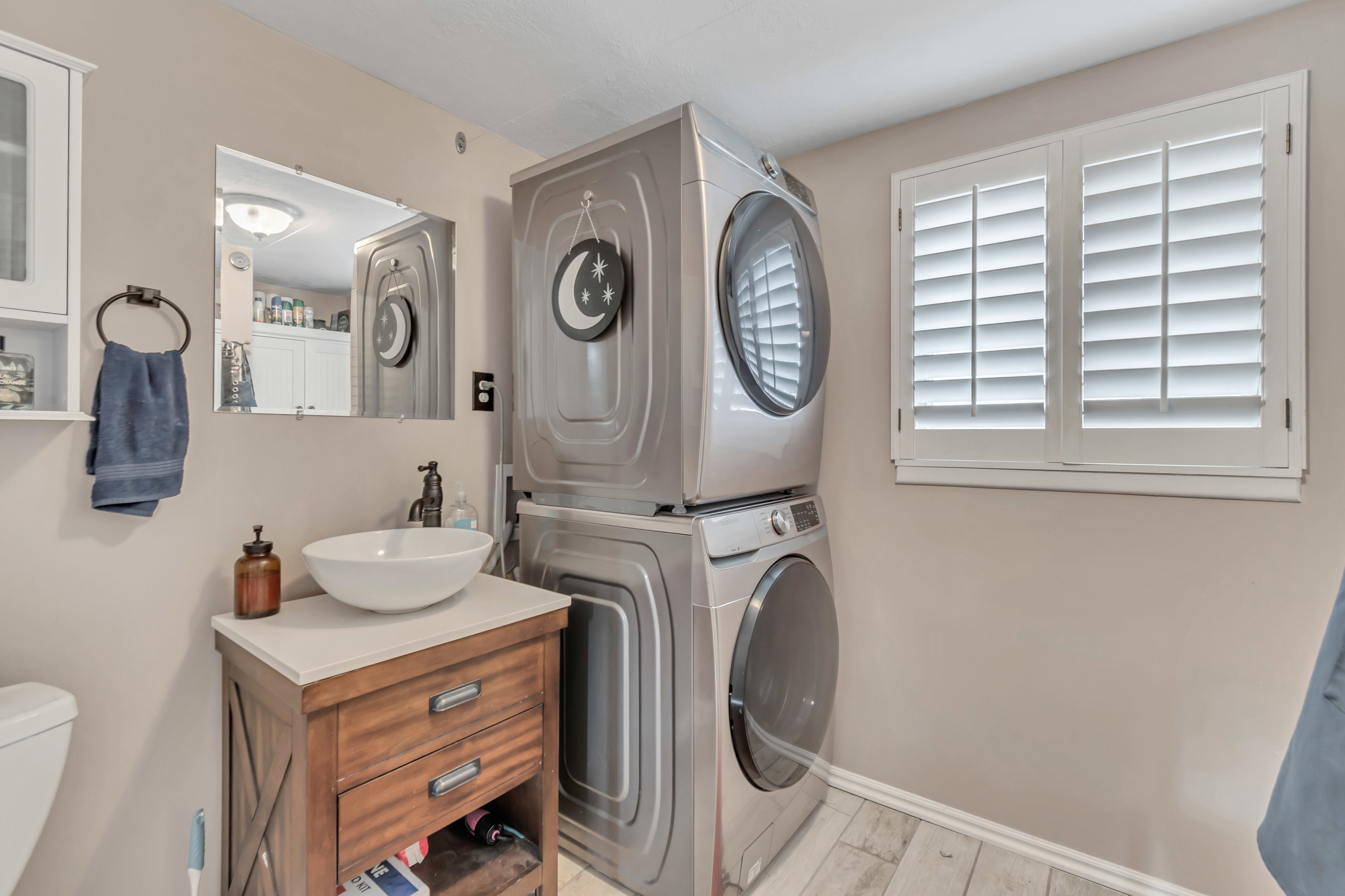 Integrated laundry appliances complement a wood-finish vanity with a vessel sink