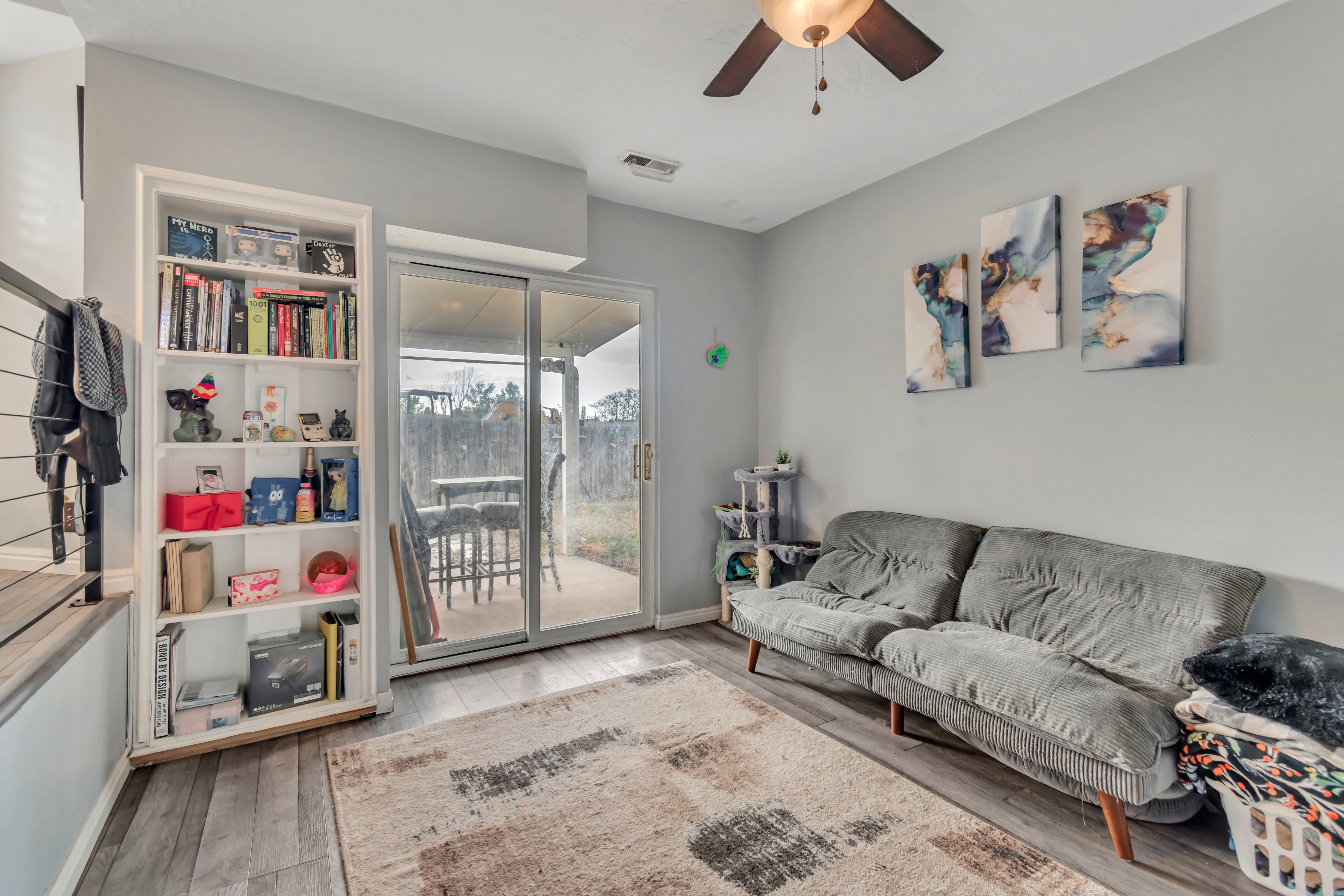 Living area featuring wood-finish flooring, a ceiling fan, and sliding glass doors opening to a concrete patio