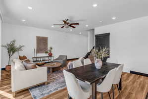 Open-concept living and dining areas featuring wood-finish flooring, recessed lighting, and white walls