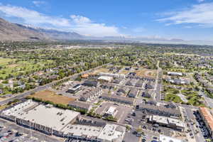 Aerial perspective showcasing a residential and commercial area with prominent mountain ranges and a large body of water in the distance