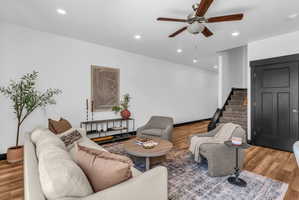 Living area featuring wood-finish flooring, recessed lighting, and a ceiling fan with wood-tone blades